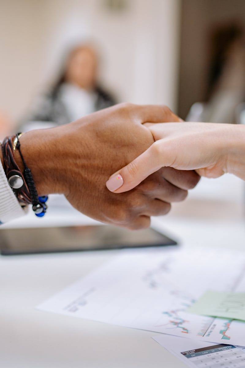Diverse business professionals exchanging handshake in an office environment, symbolizing agreement.